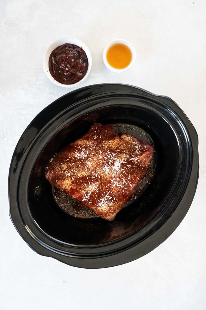 This easy slow cooker pulled pork recipe makes the best bbq pulled pork sandwiches, sliders, tacos, nachos and more! It's saucy, flavorful and so tender! One of our favorite crock pot recipes for feeding a crowd or a family dinner. Seasonings sprinkled on uncooked pork butt in slow cooker.